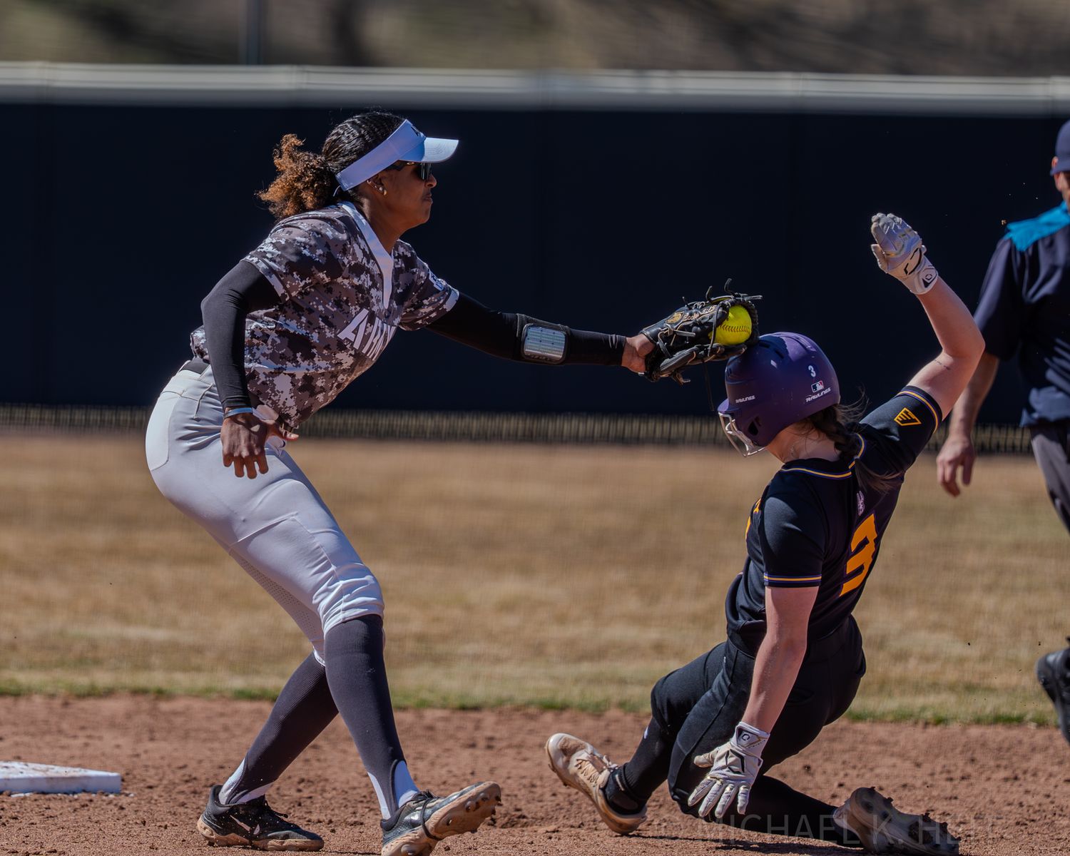 Dramatic play at home plate between catcher and baserunner during softball game.