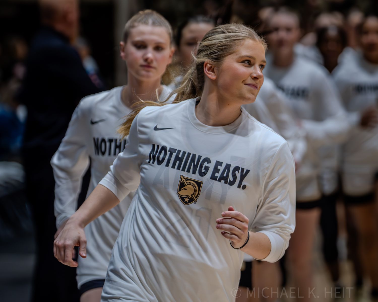 Athletes in white uniforms with 'Nothing Easy' text warm up before a game.