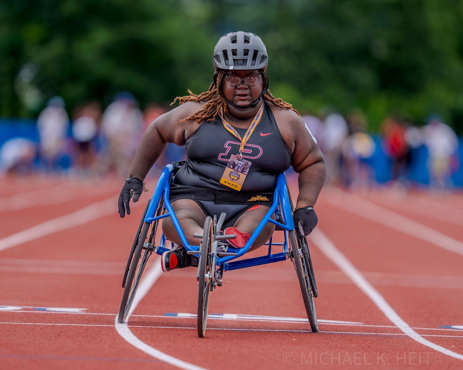 Wheelchair racing athlete competing on outdoor track during competition.