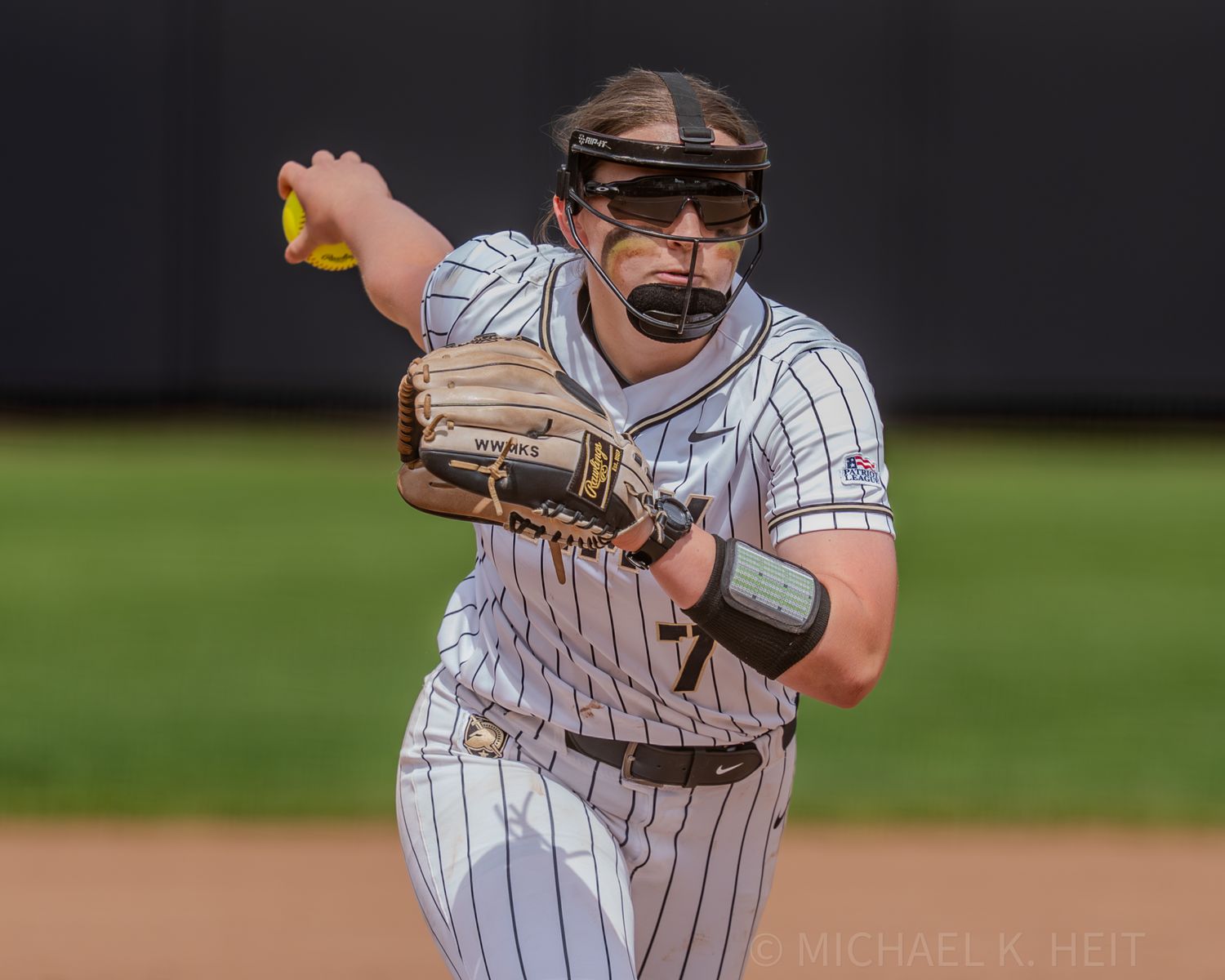 Softball player in pinstriped uniform preparing to throw the ball.