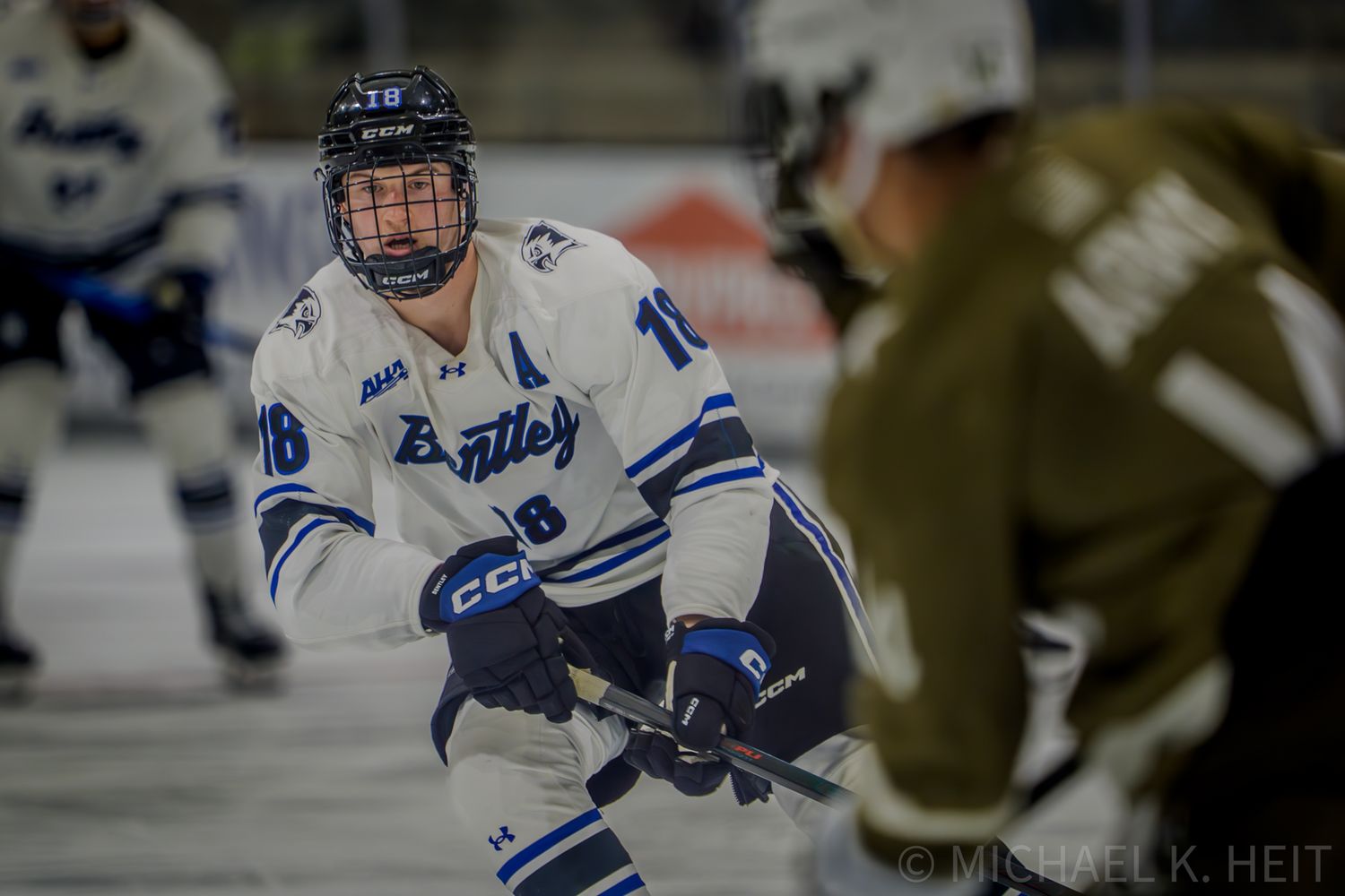 Bentley and Army Hockey players compete for puck possession during intense game action on the ice.