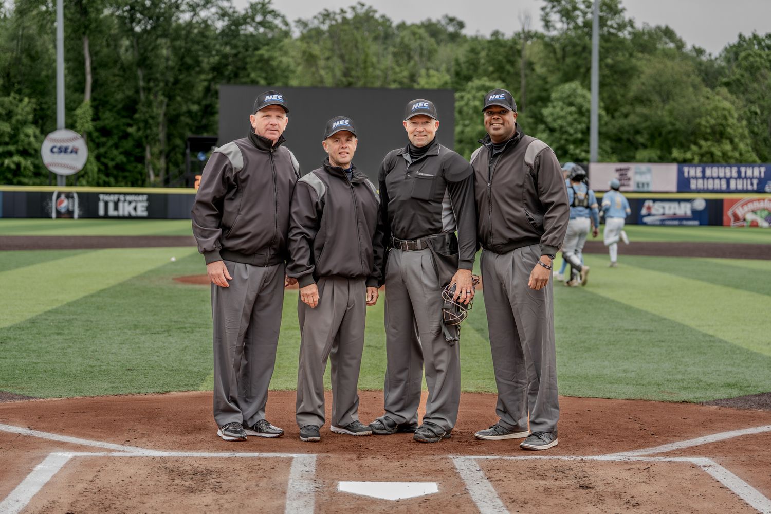 Baseball umpires in grey uniforms stand together on a baseball field during a game.