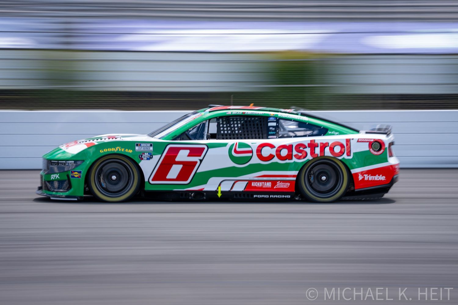 NASCAR No. 6 Castrol-sponsored green and white race car speeding on track during a race event.