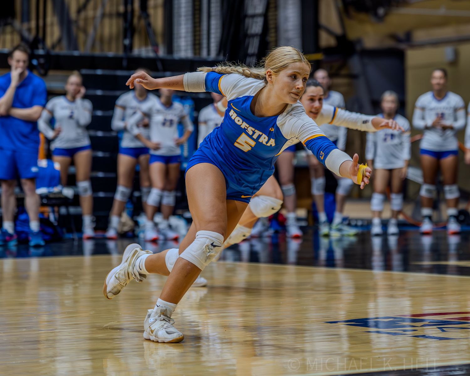 Volleyball players make diving defensive plays on the hardwood court.