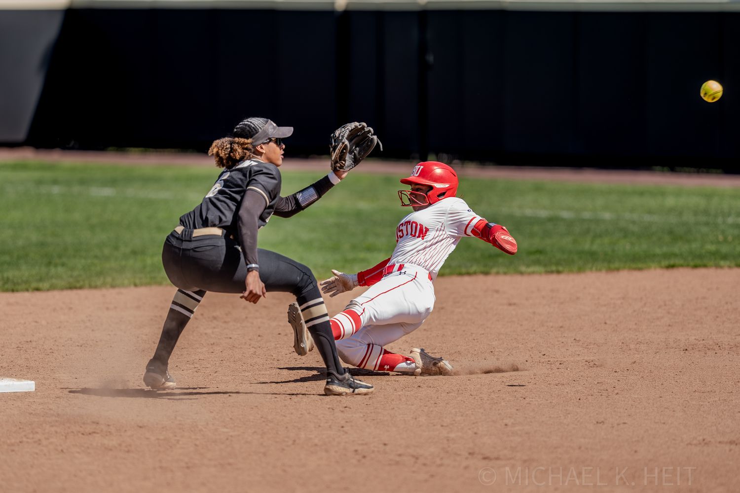 Action shot of softball players during a sliding play at second base.