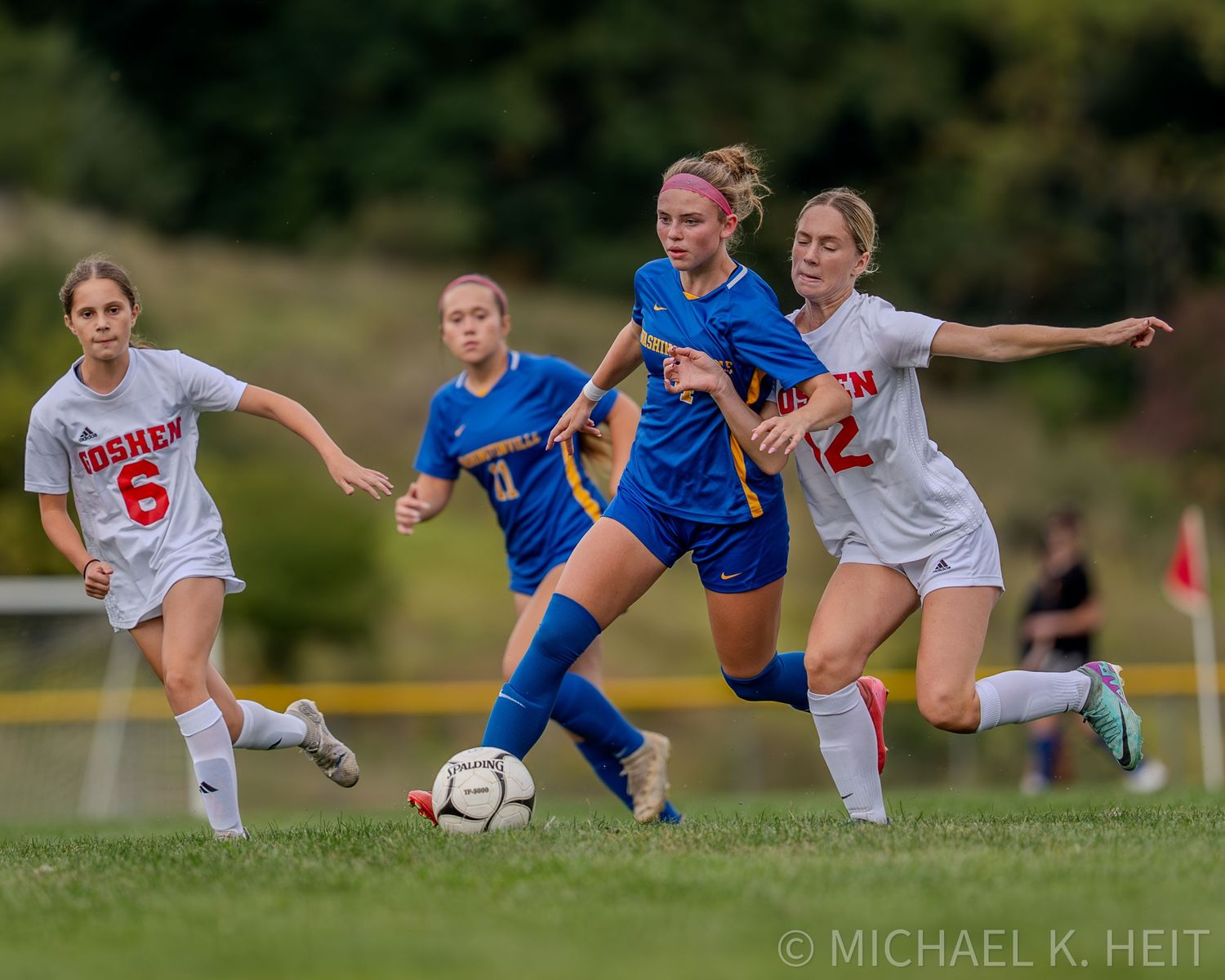 High school soccer players compete for possession of the ball during an intense match between two teams.