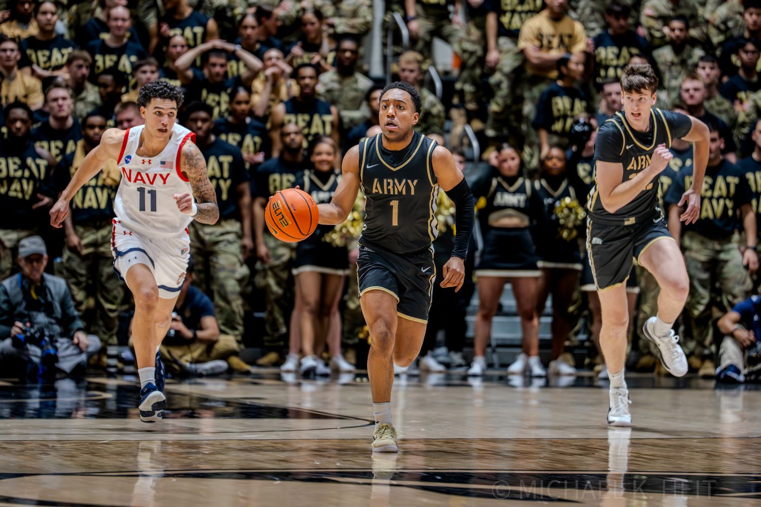 Basketball players compete for possession during an intense game with spectators in attendance.