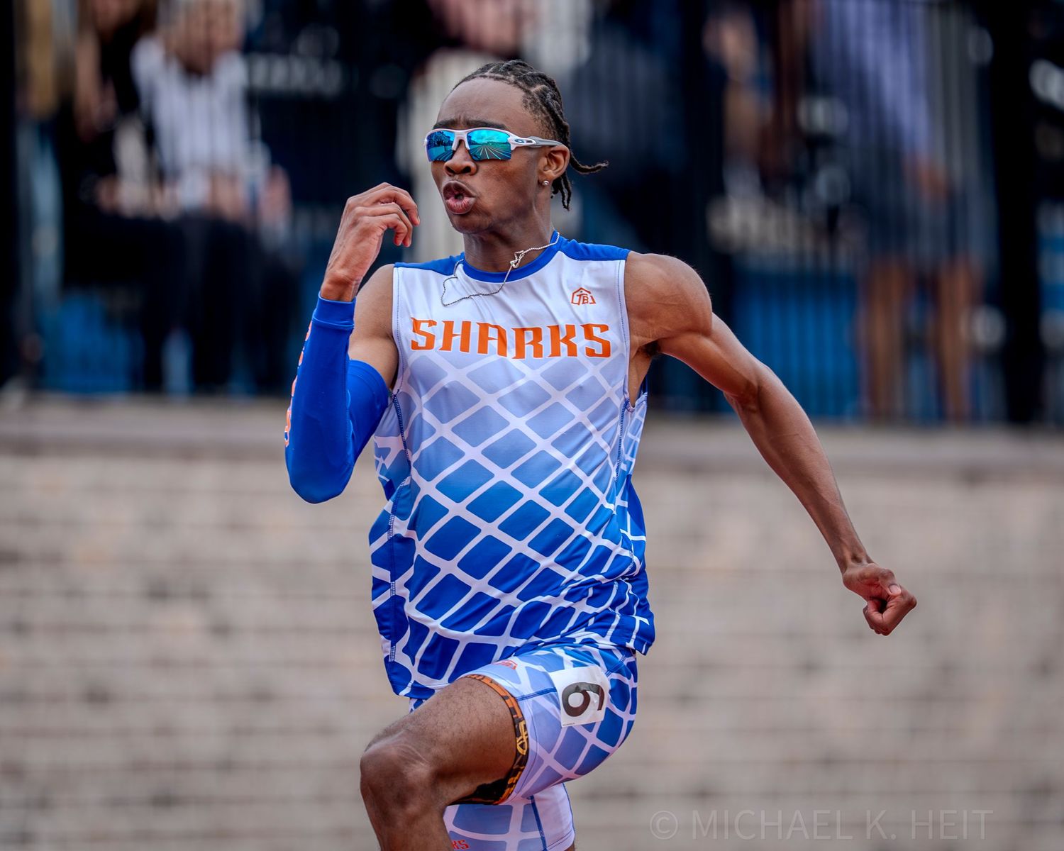 Runners in blue uniforms compete intensely during a track meet.