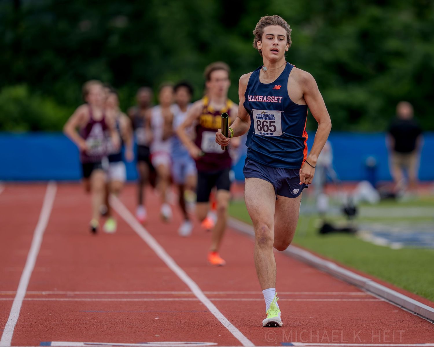 Athletes competing in long jump at an outdoor track and field competition.