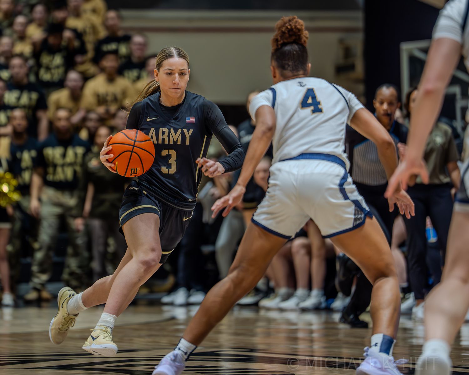 Army and Navy women's basketball teams battle for control of the ball during a fast-paced game.