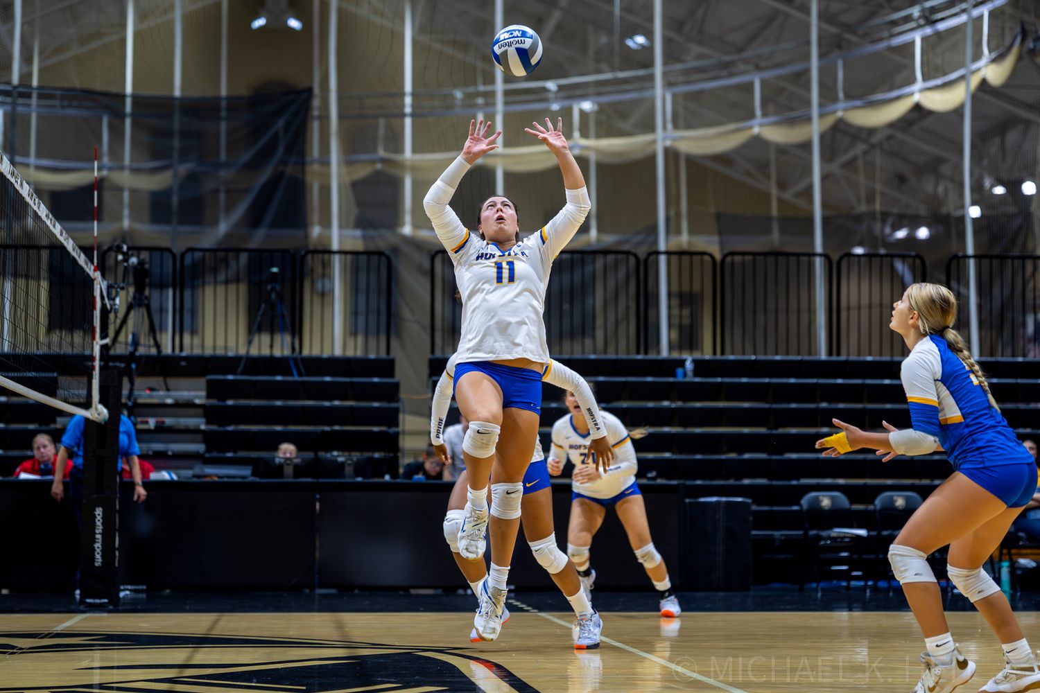 Athletes dive and stretch across the volleyball court to save a play.