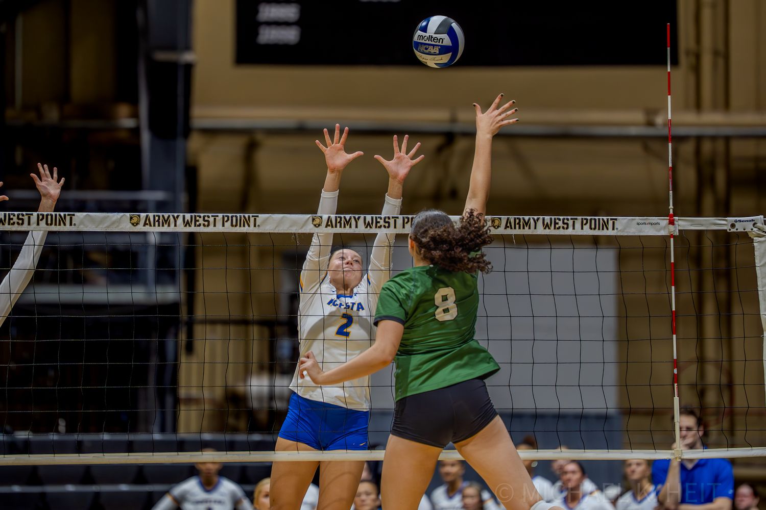 Players from opposing teams battle at the net during a volleyball match.