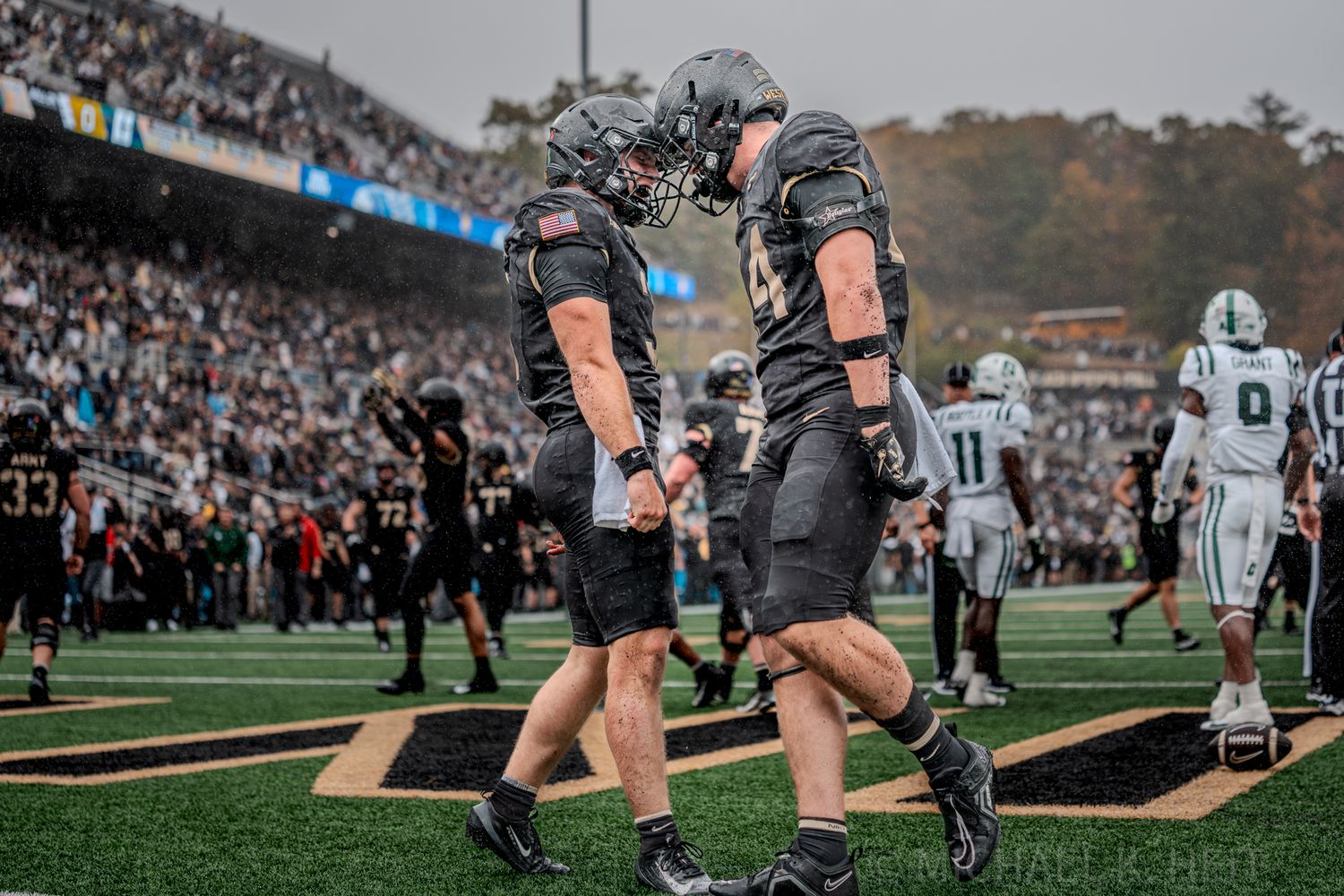 Two players celebrate on the field during an Army football game.