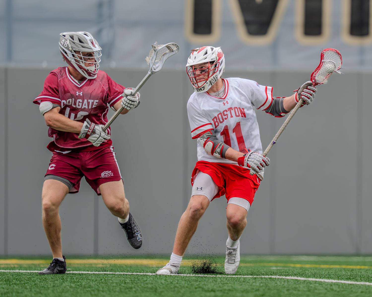 College lacrosse match showing players from opposing teams competing for ball possession.