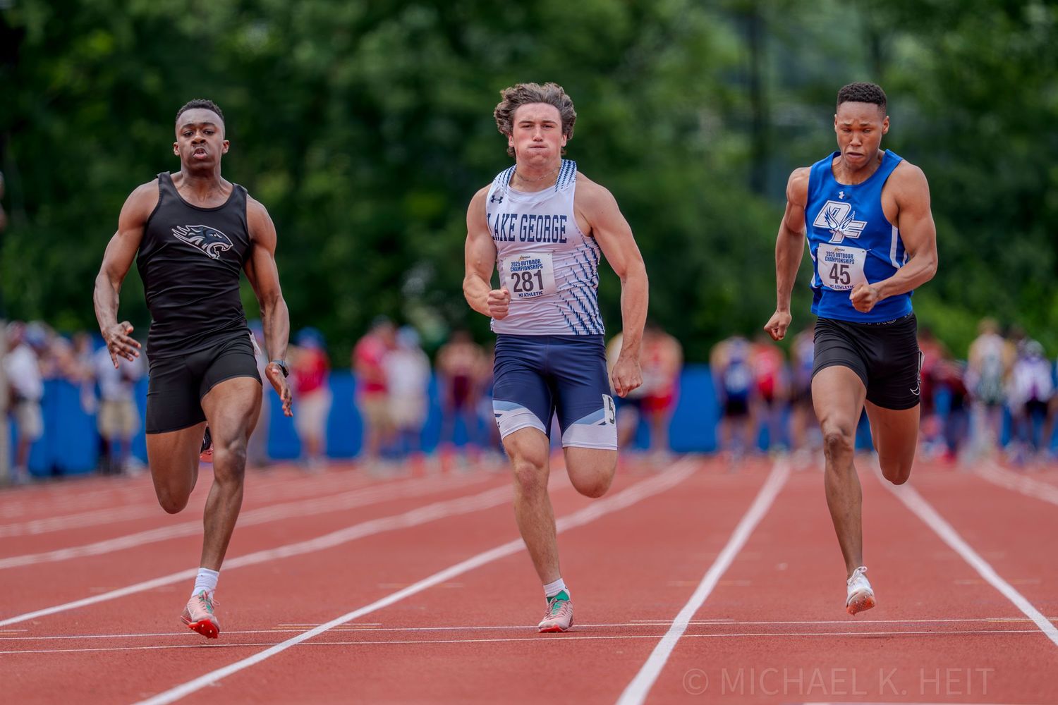 Track athletes compete in a sprint race on an outdoor track.