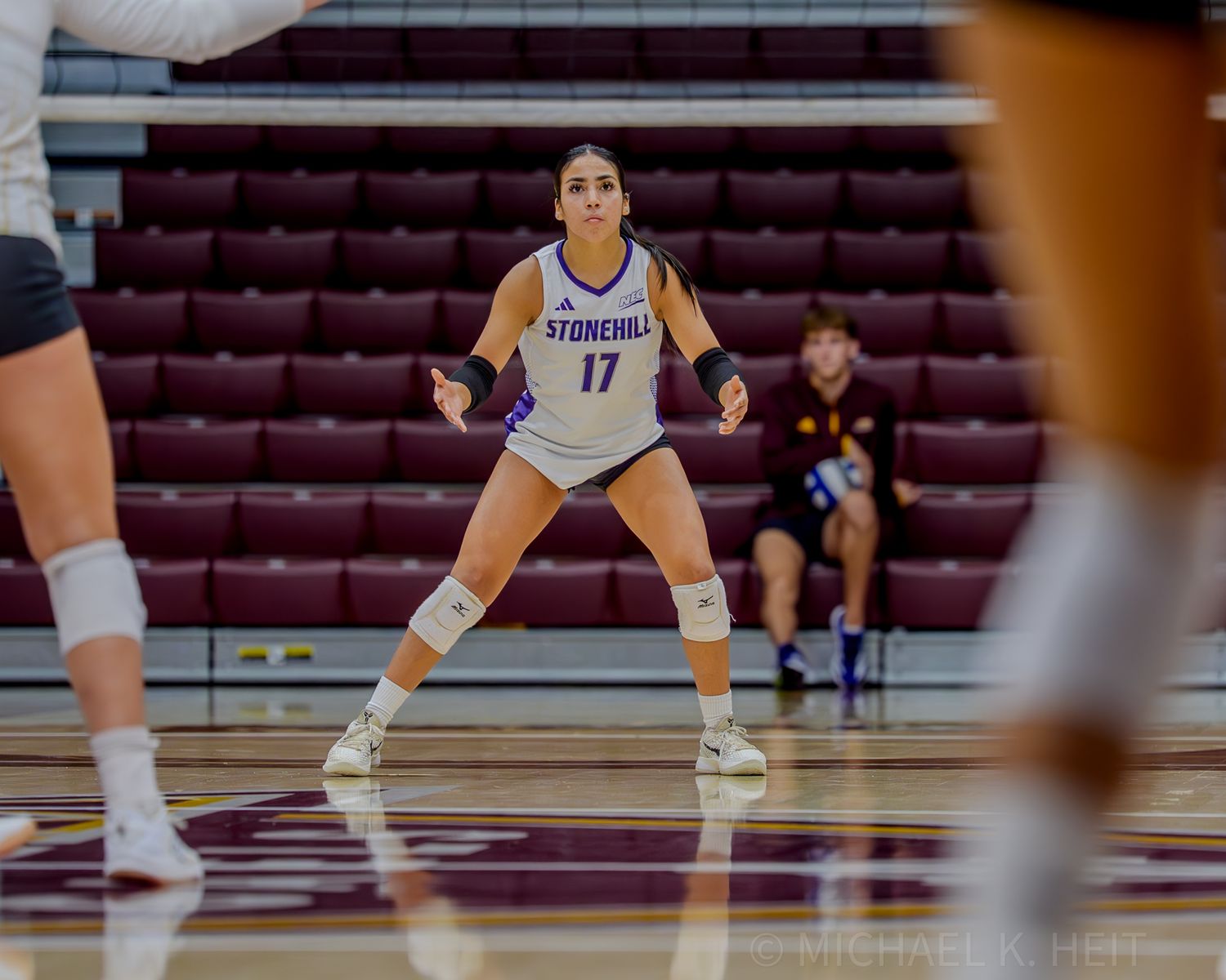 A volleyball player in defensive stance prepares for the next play.