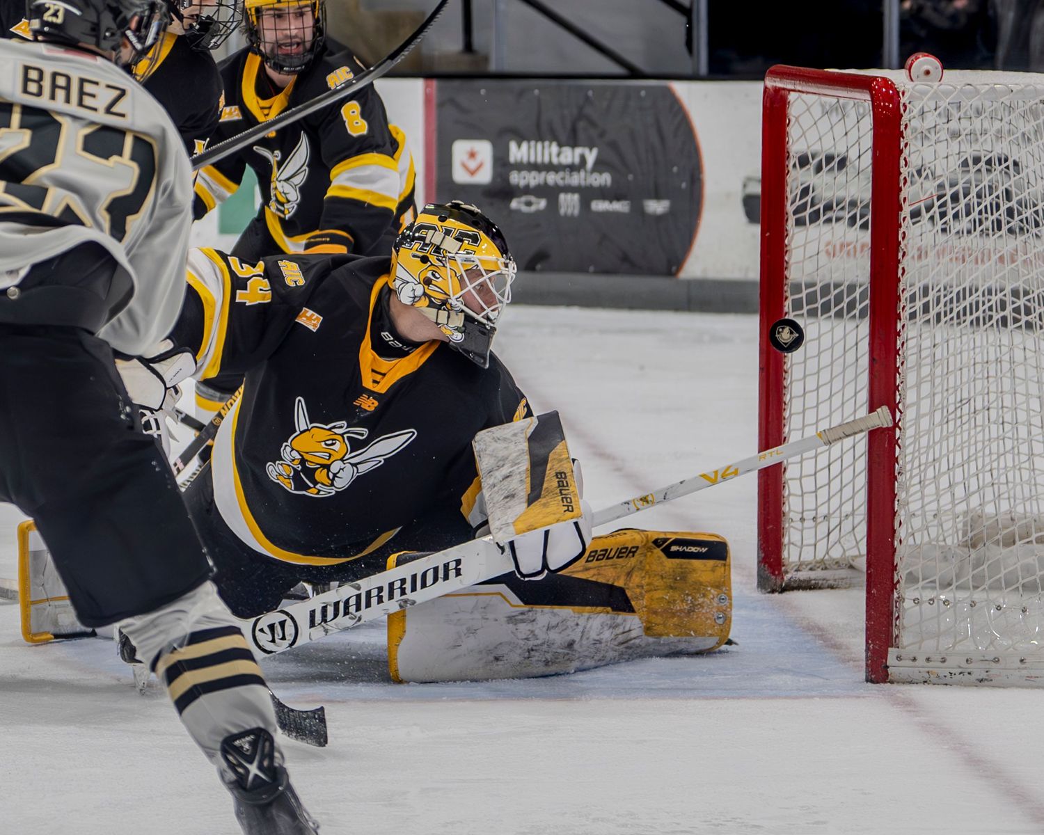Hockey goalie makes a diving save attempt in front of the net.