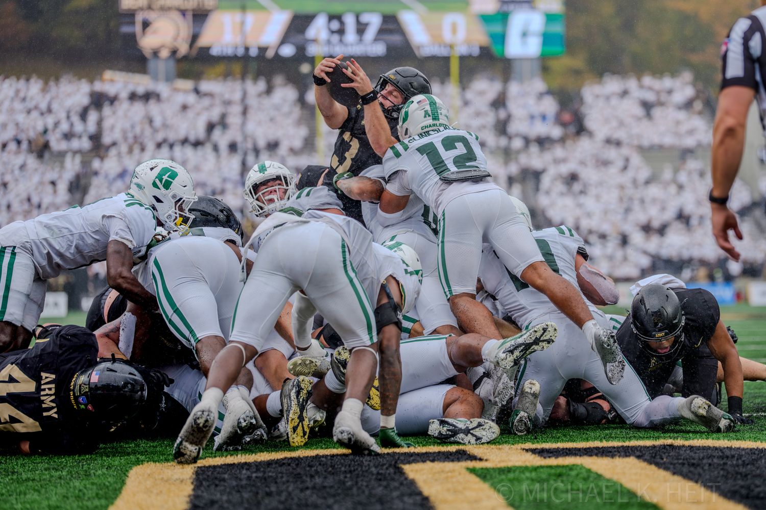 Football players line up at the line of scrimmage during a game with players in green and white uniforms.