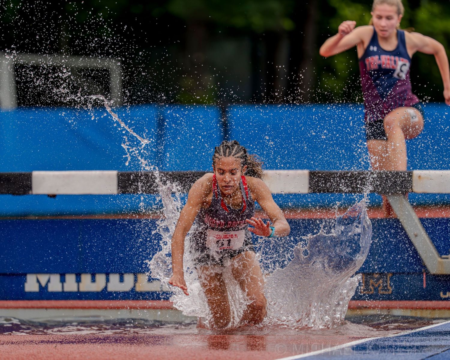 Athletes splash through water obstacles during a steeplechase competition.