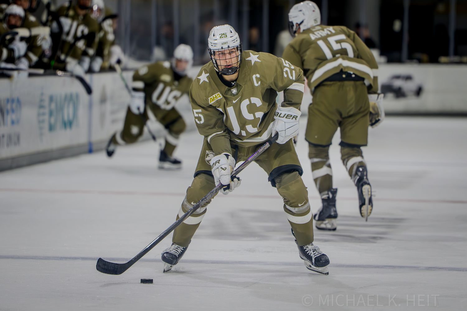 Hockey players in gold and white uniforms skate on ice during an intense game at an indoor arena.