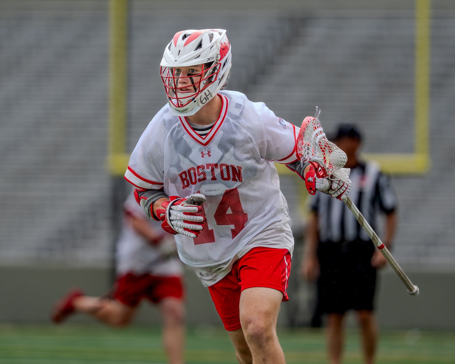 College lacrosse players in white and red uniforms compete during an intense match on the field.