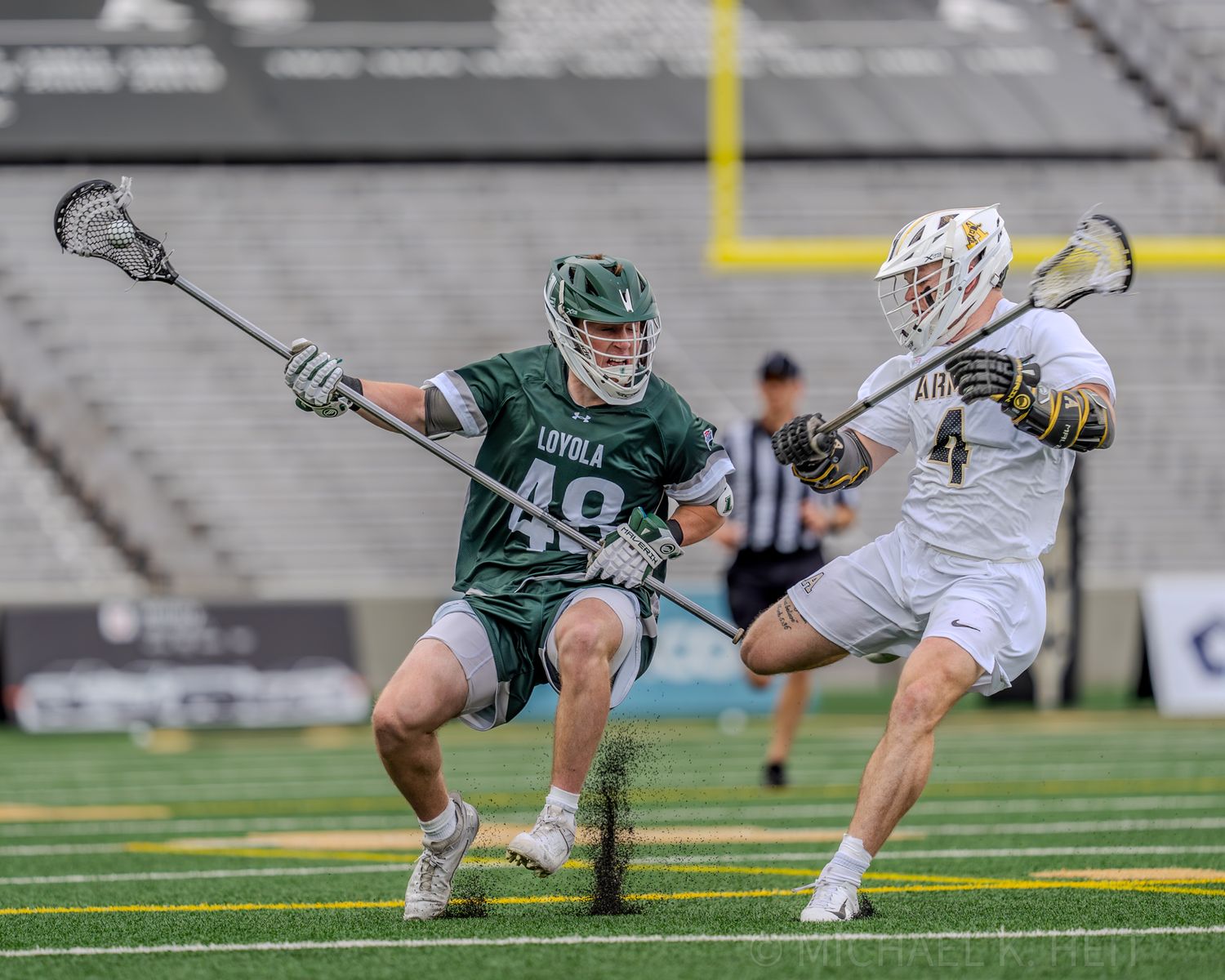 Lacrosse players from opposing teams battling for possession on the turf field.