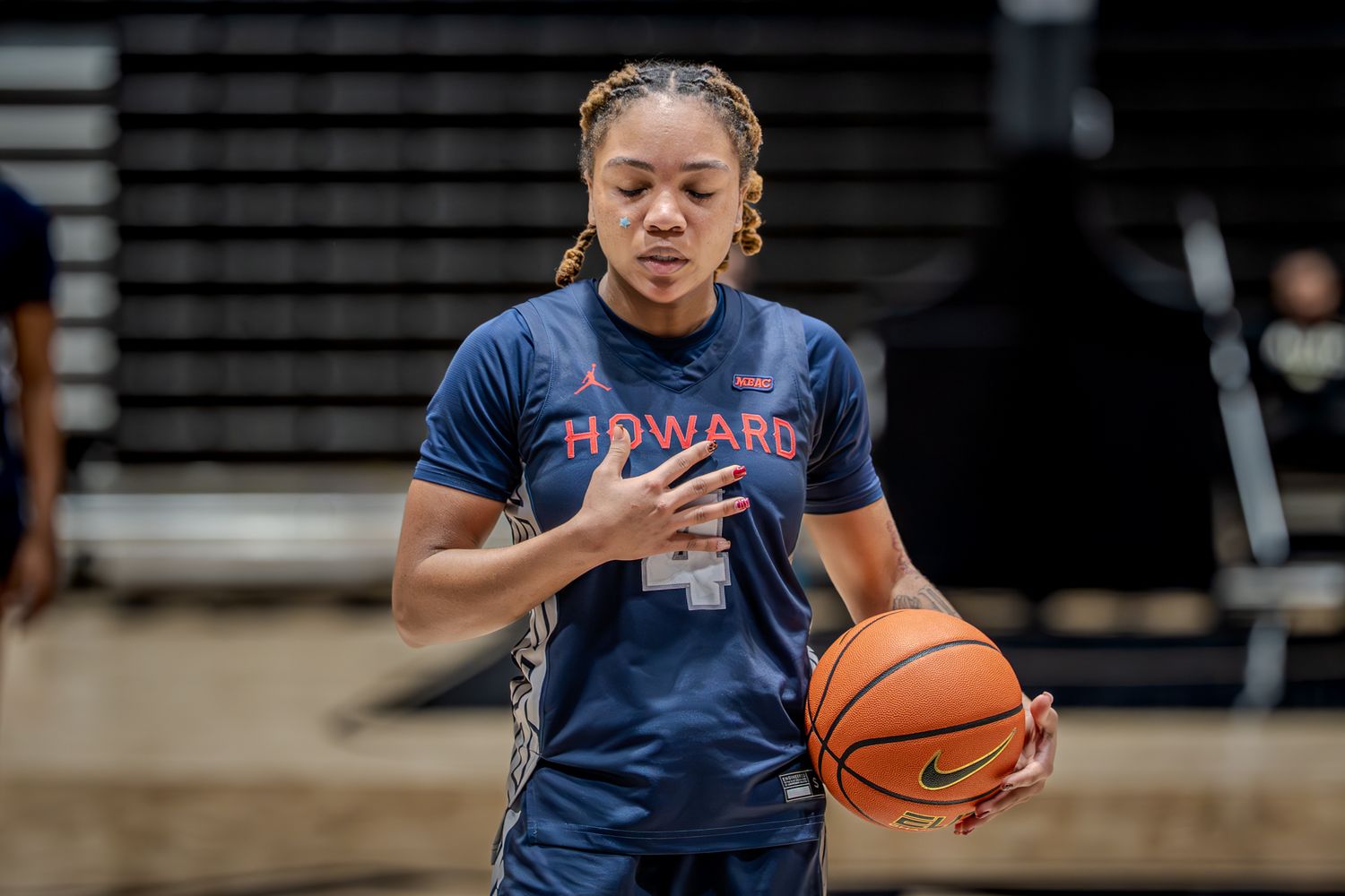 Basketball players in navy blue uniforms practice on a court during training.