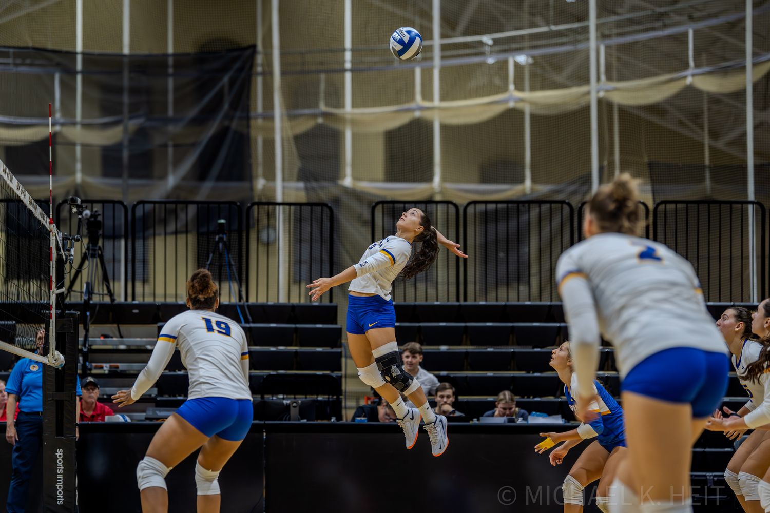 Volleyball players position themselves for a play during an indoor match.