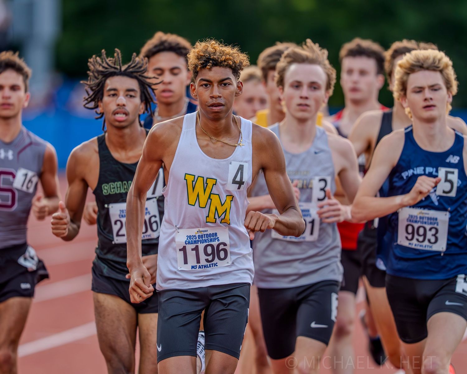 Athletes compete in a crowded track race with multiple runners vying for position on the track.