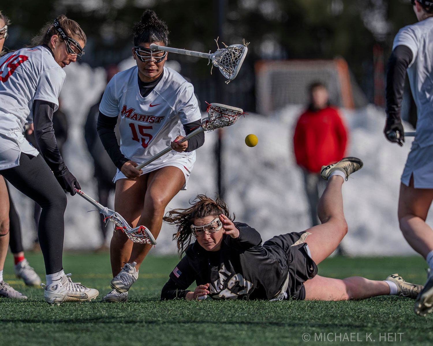 A sequence of lacrosse players diving and reaching for a ground ball during an intense game moment.