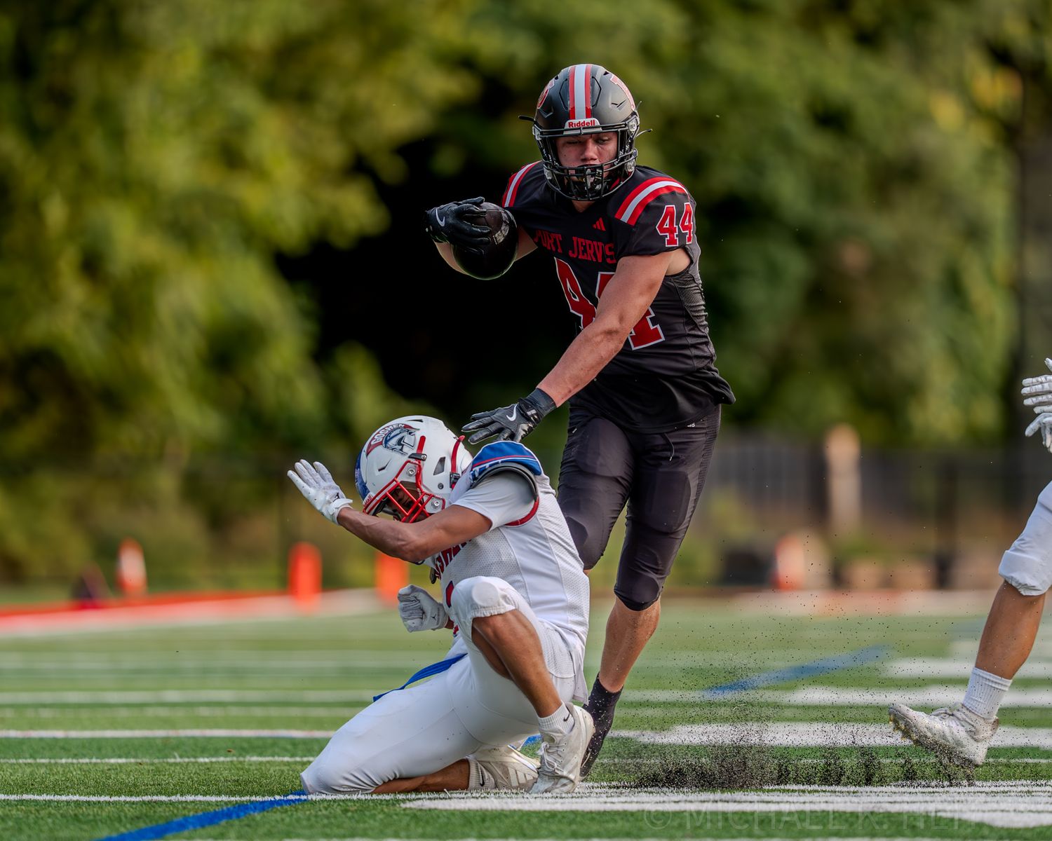 Football players engage in a ground battle near the sideline during a competitive match.