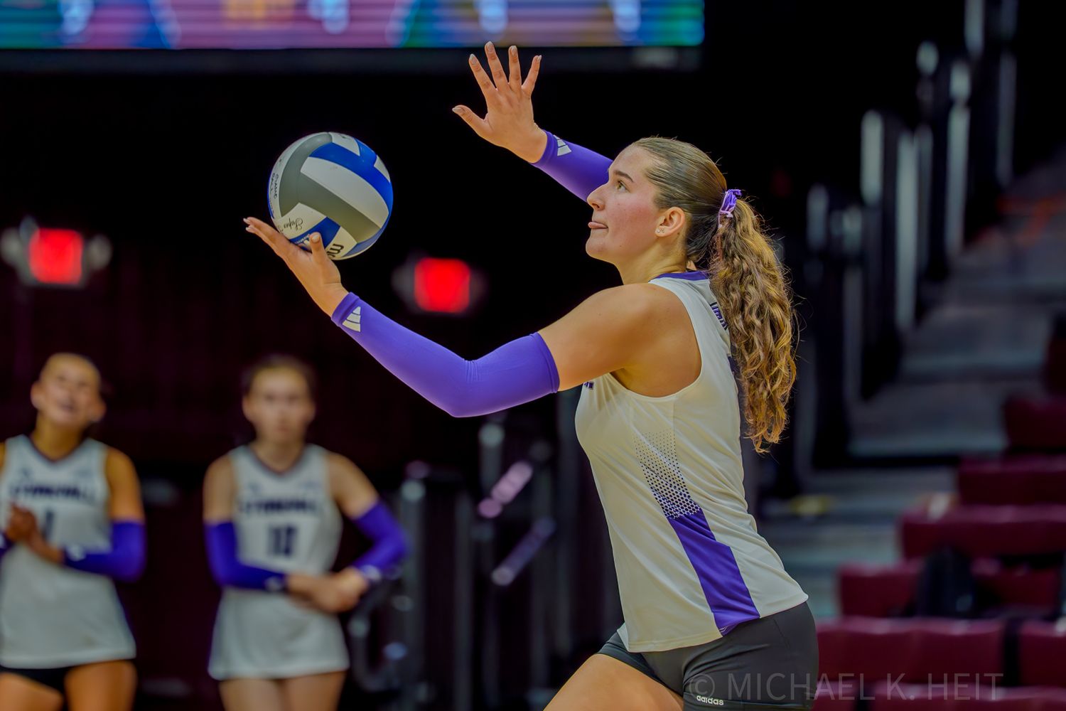 Athletes jump to block a volleyball during a competitive indoor game.
