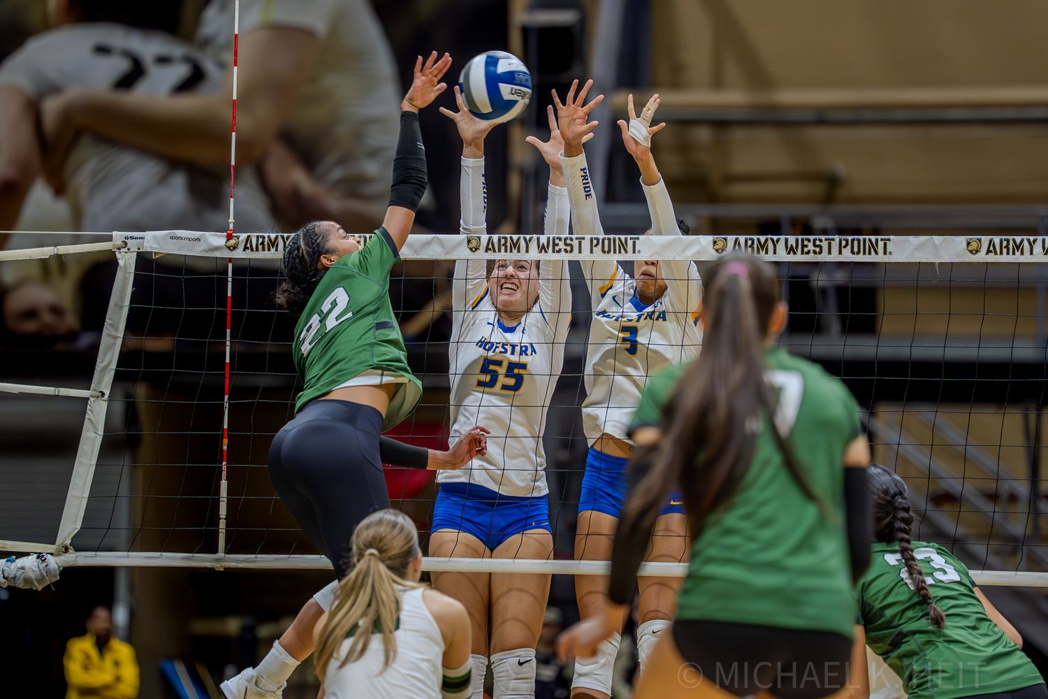 Players leap high at the net attempting to block a volleyball spike.