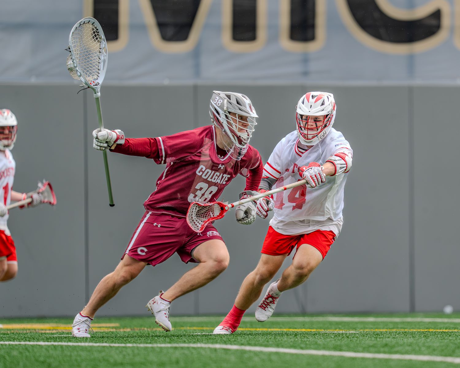 Dynamic action shot of lacrosse players competing for ball control during collegiate match.