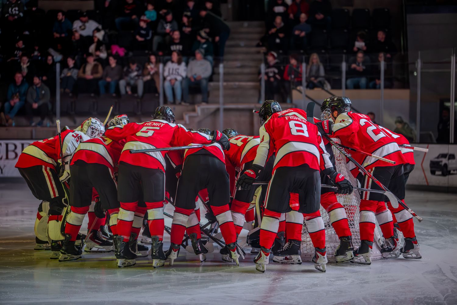 Hockey players gather in a circle formation on the ice before a game in a pre-game ritual or huddle.
