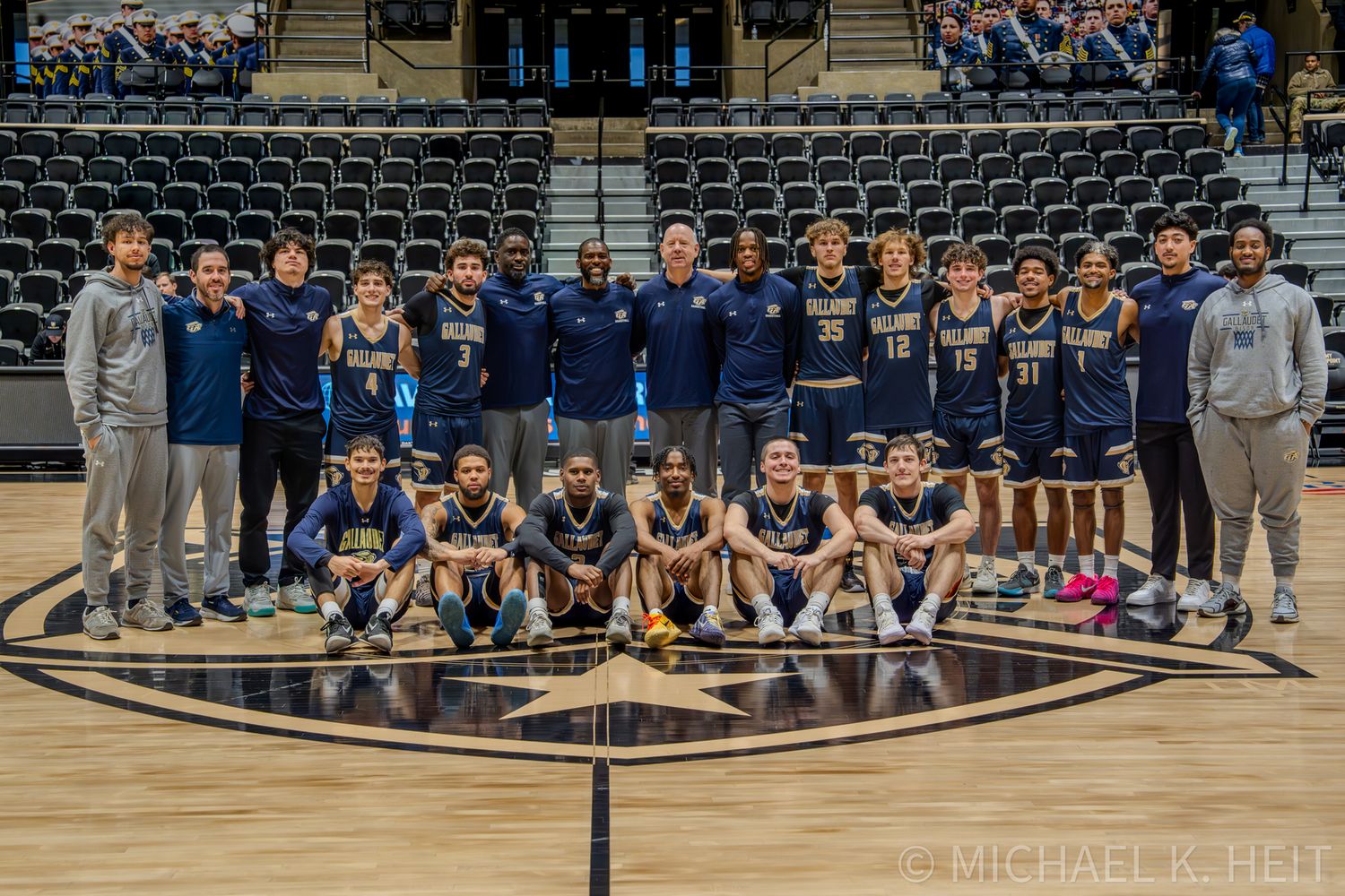 Wide view of basketball teams and coaching staff lined up on court before game start.