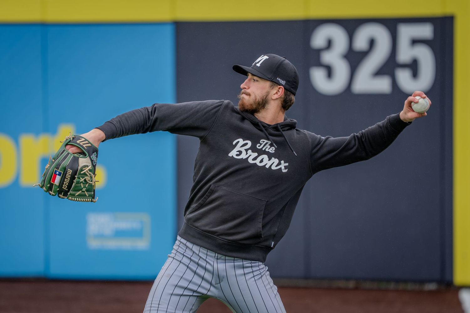 Baseball player in pinstriped uniform throws a pitch from the mound during a game.