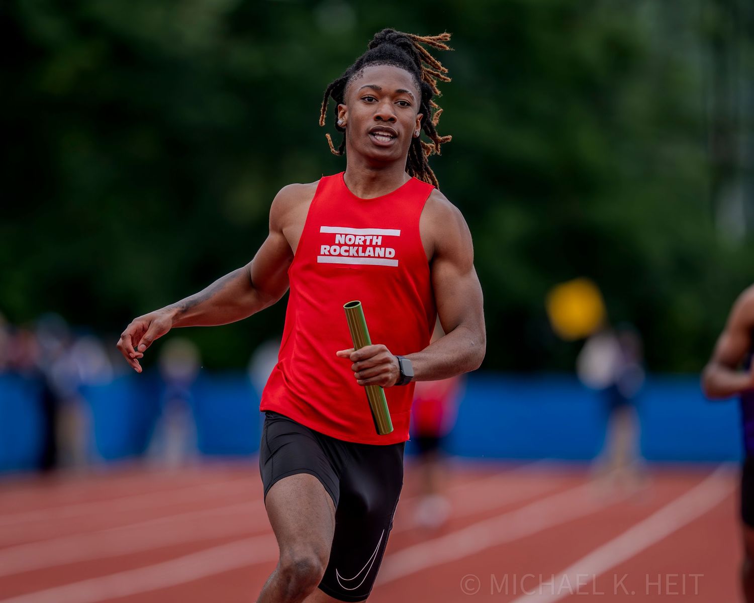Track athletes competing in a sprint race on an outdoor track.