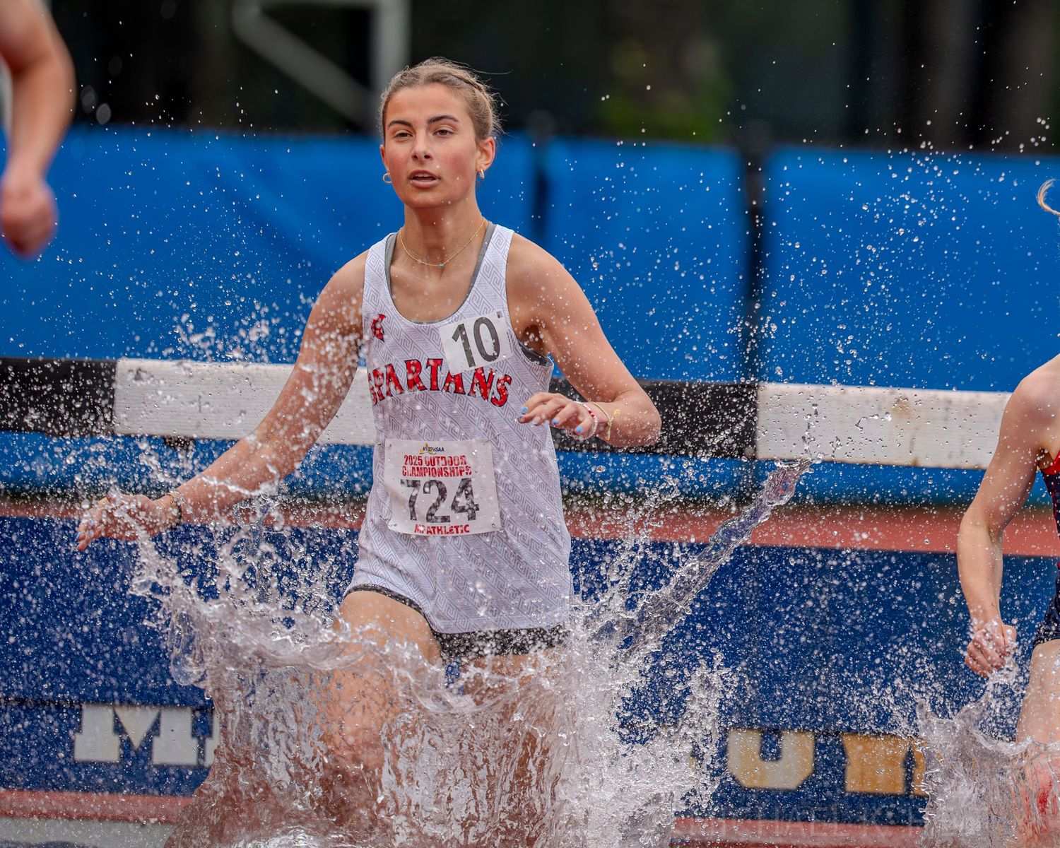 Runners navigate through water jumps in a steeplechase event.