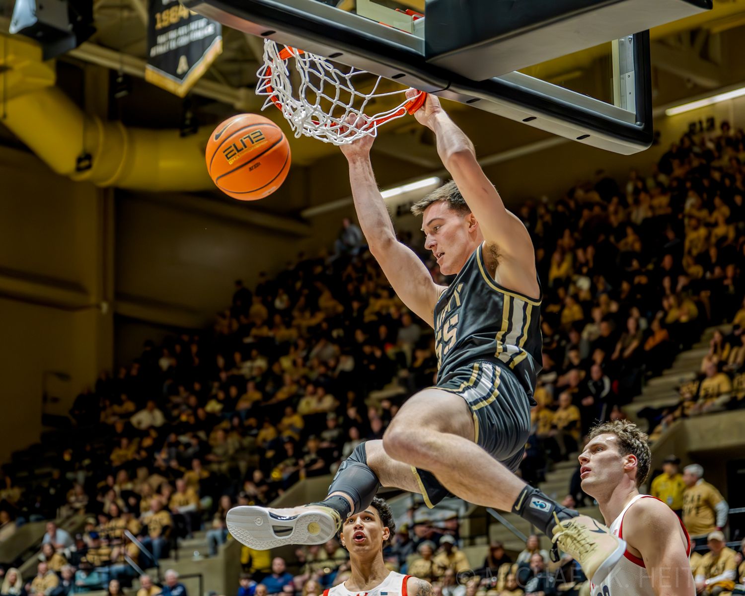 Players from Army and Navy jump for a rebound under the basket during competitive game.