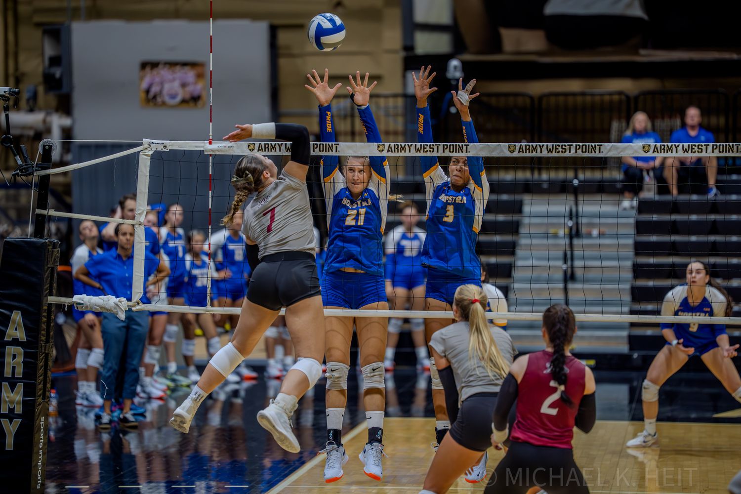 Indoor volleyball match with players positioned at net for play.