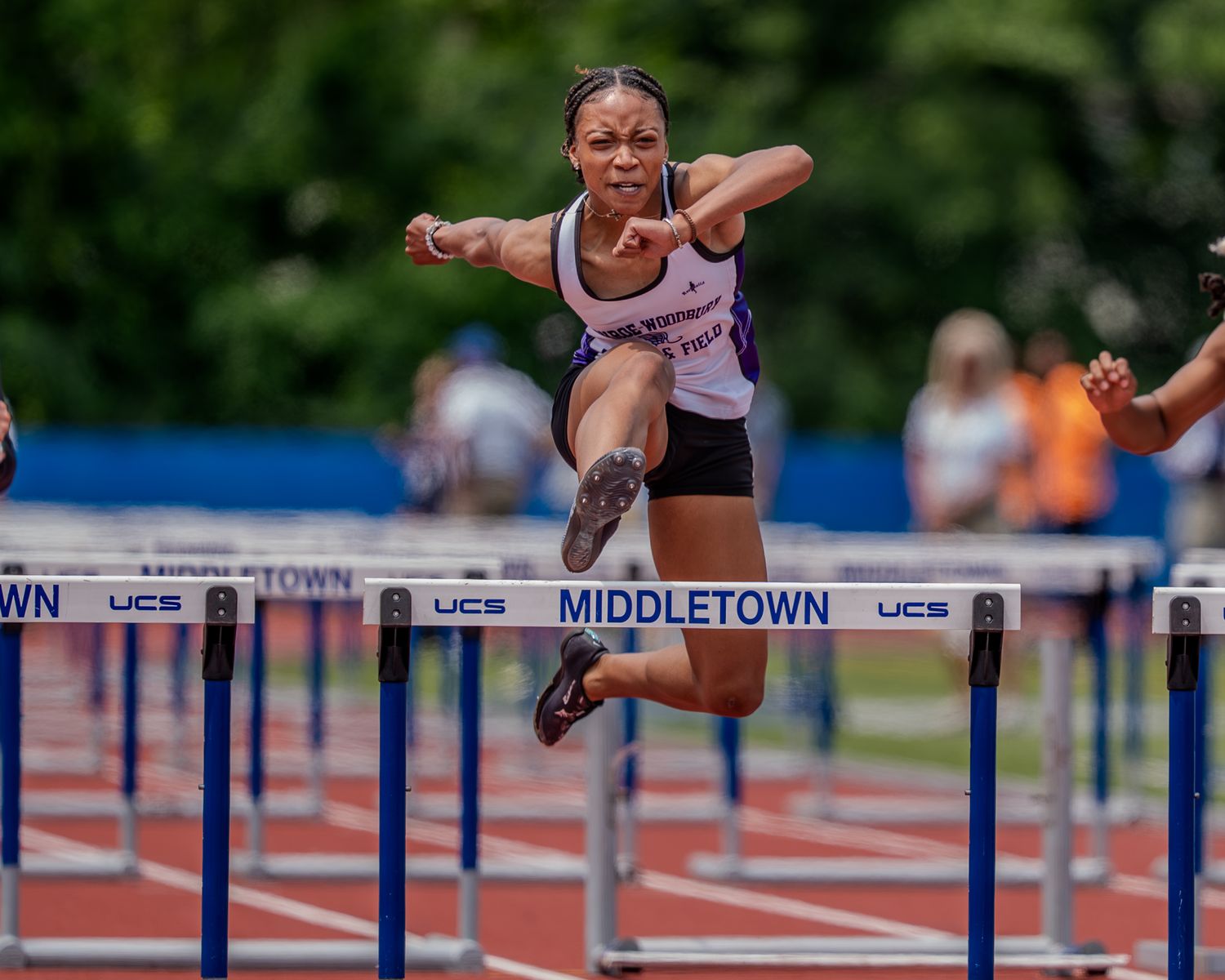 Athletes competing in a track and field hurdles race on an outdoor running track during a competition.