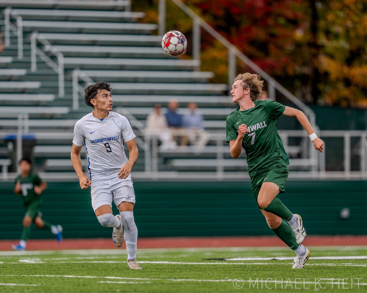 Soccer players from opposing teams compete for control of the ball during an intense match on the field.