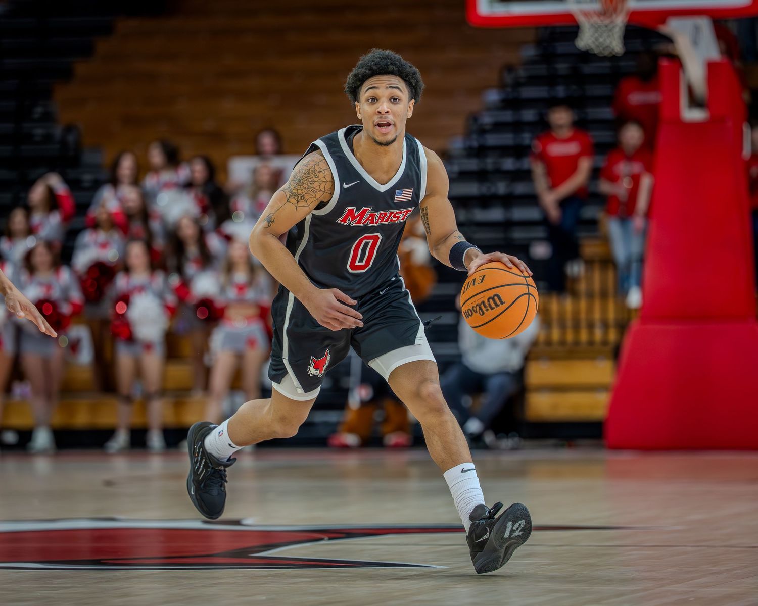 Basketball player in a black jersey dives for a loose ball during an intense game.