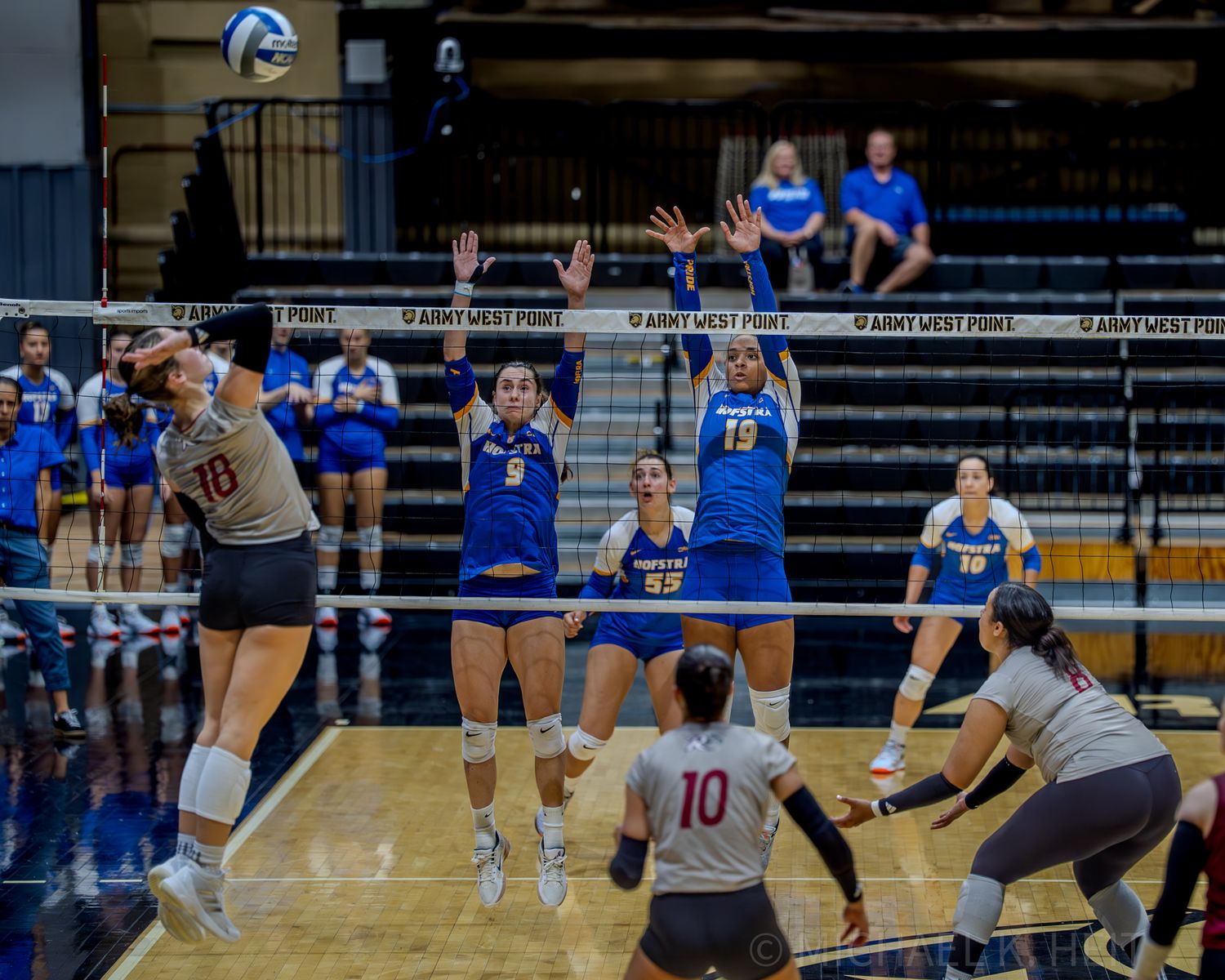 Volleyball players positioned on court during competitive game play.