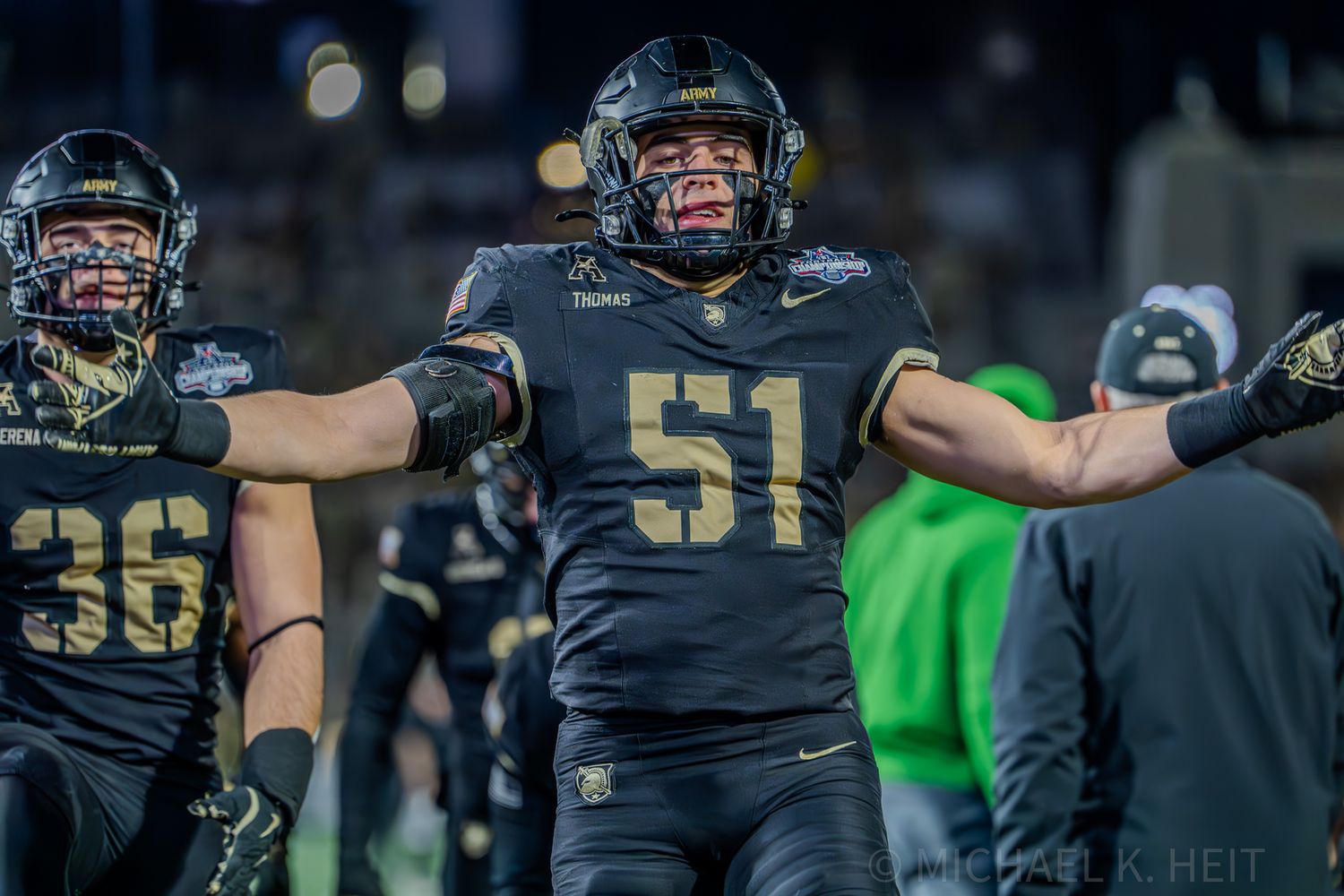 Players in black uniforms line up on football field during game action.