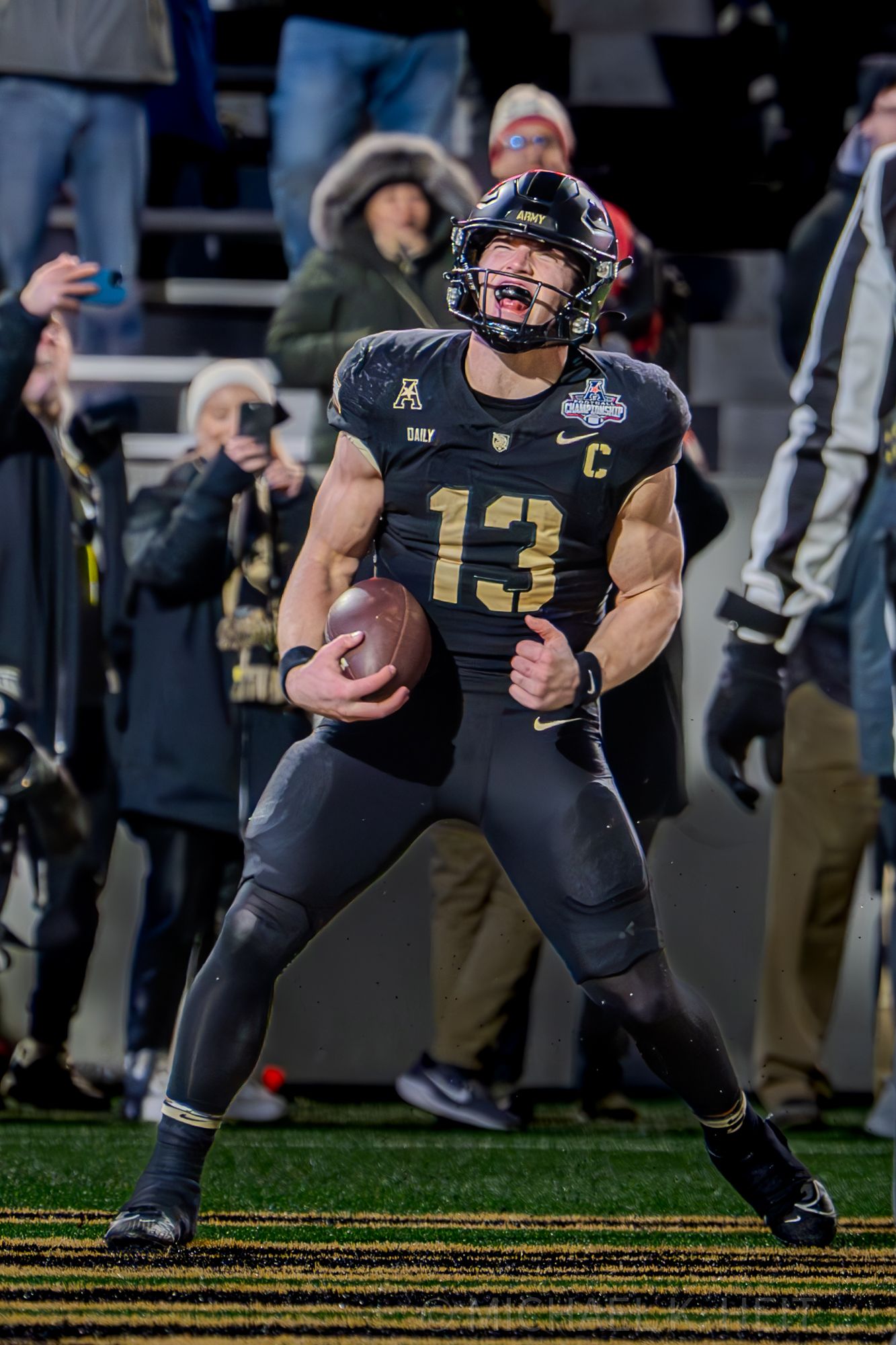 Football player in black uniform celebrates on field during game.