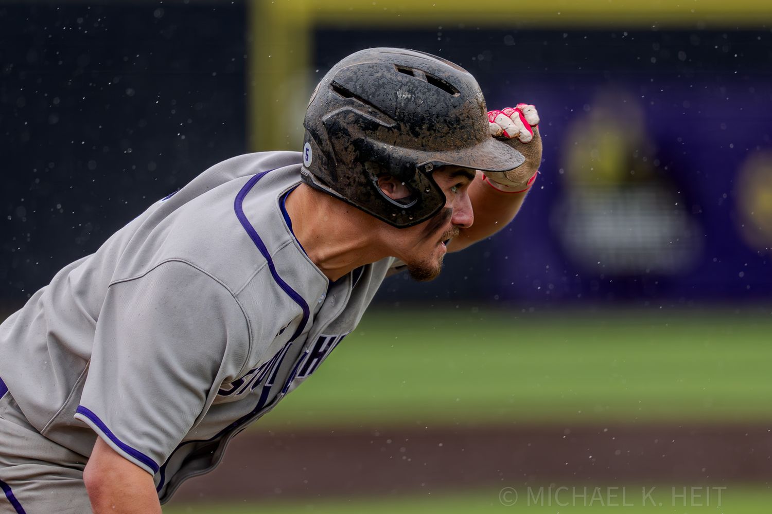 Baseball player in gray uniform takes batting stance at home plate.