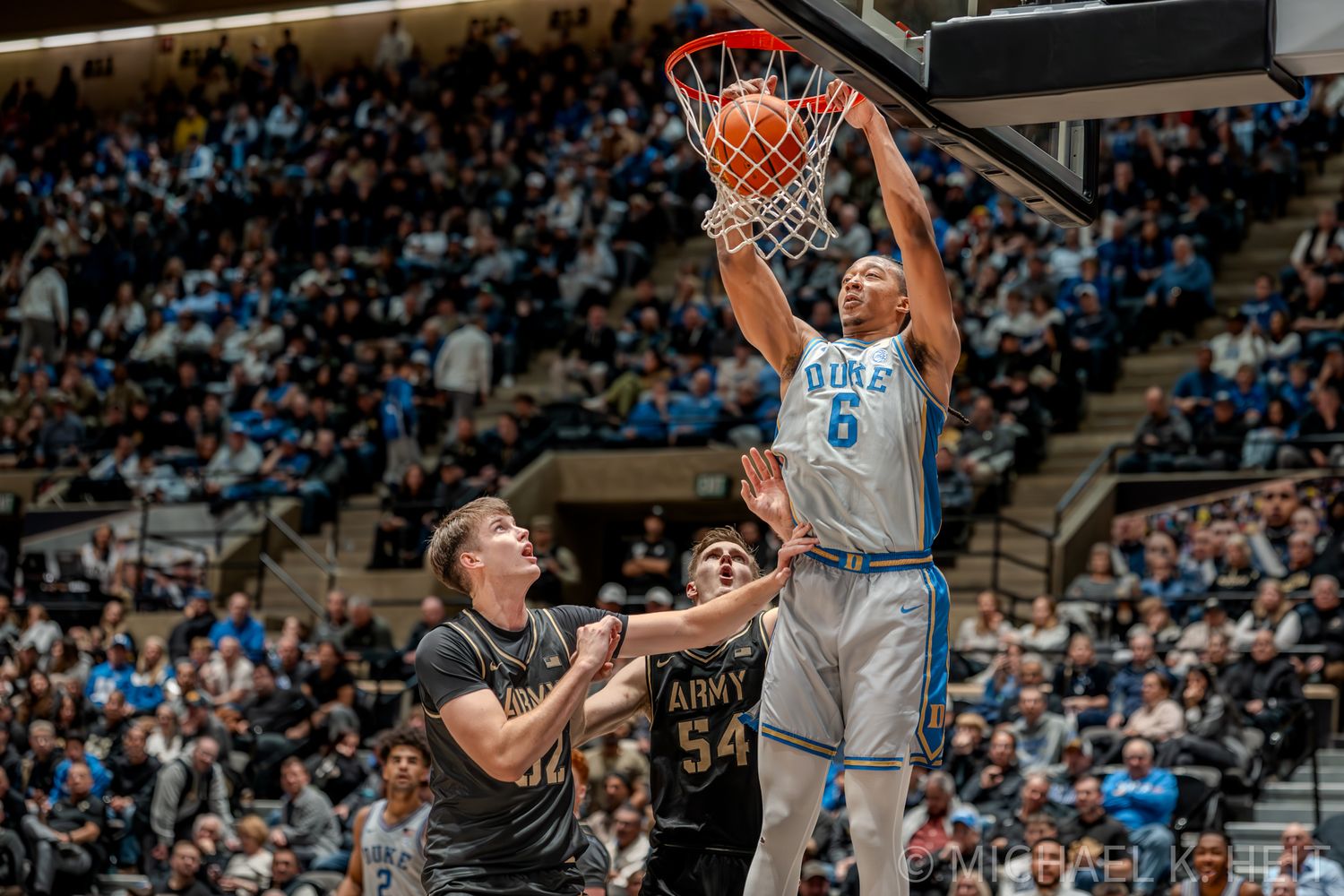 Basketball player executes a powerful slam dunk over defenders during a game.