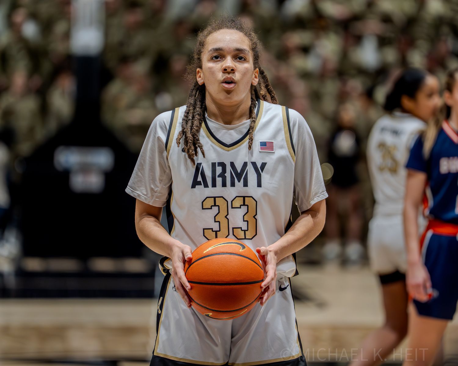 Basketball players from Army and opposing team compete during a competitive match.